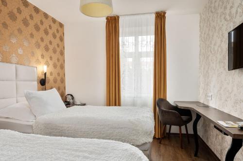 a hotel room with two beds and a desk and a window at Hotel MAXPLAZA in Trnava