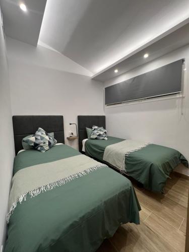 two beds in a room with green sheets at V Macaronesia in San Bartolomé