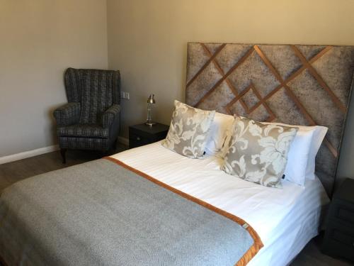 a bedroom with a large bed and a chair at Michelangelos - Rooms, Restaurant & Bar in Gateshead