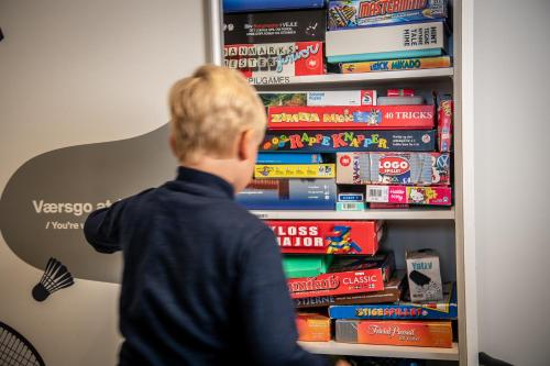 a boy is looking at a book shelf filled with books at Kolding Hotel Apartments in Kolding