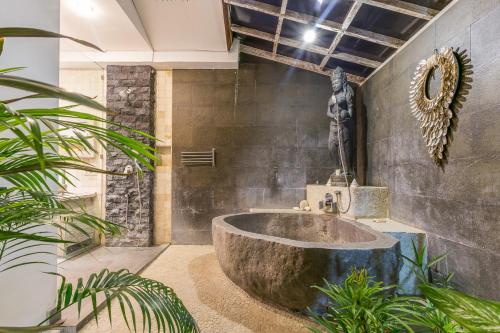 a bathroom with a large stone tub in a room with plants at Villa Maloa in Denpasar