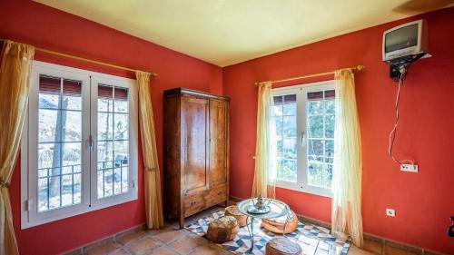 a room with red walls and two windows and a tv at Casa Mulera Alozaina by Ruralidays in Alozaina