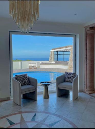 a room with two chairs and a table and a pool at Casa das Rosas in Carvoeira