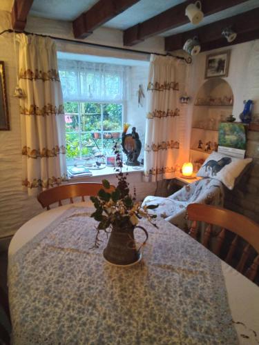 Una habitación con una mesa con un jarrón de flores. en Emms Cottage en Par
