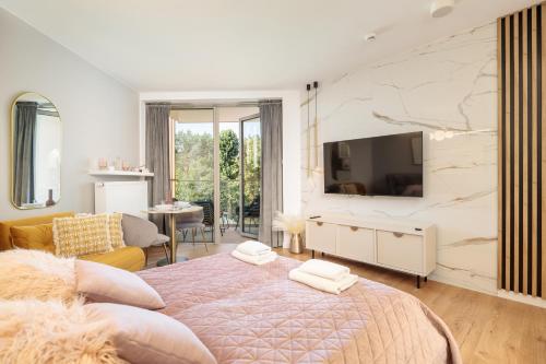 a bedroom with a bed and a tv on a wall at Pinea Premium 4YOU Baseny i Sauna w cenie !!! in Pobierowo