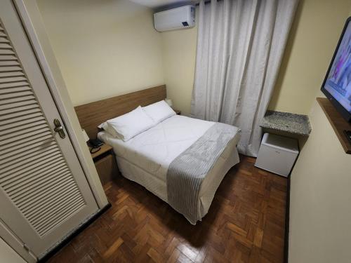 a small bedroom with a bed and a television at Pousada Catedral in Petrópolis