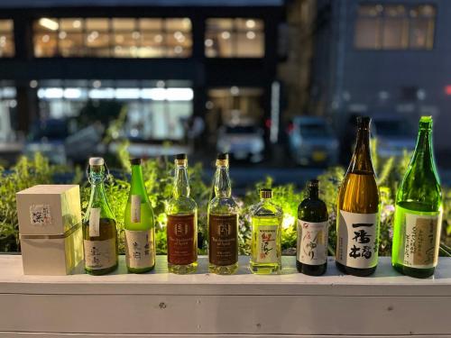 a row of bottles of alcohol sitting on a table at En- Hostel & Café bar in Amami