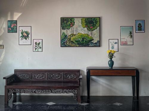 un banc et une table avec un tableau sur le mur dans l'établissement Aui Hotel, à Ðoan Xá