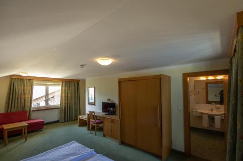 ヴェルグルにあるHotel Schachtnerhofの赤いソファとバスルームが備わるホテルルームです。