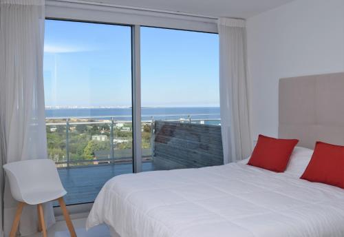 a bedroom with a white bed and a large window at SYRAH Bahía by depptö in Punta del Este