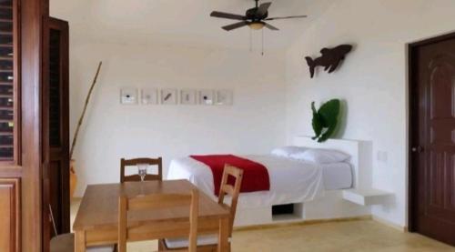 a bedroom with a bed and a table and a ceiling fan at Bungalow de Ballenas in Punta Balandra
