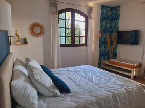 1 dormitorio con cama con almohadas y ventana en Domaine des Pins, en Saint-Estève