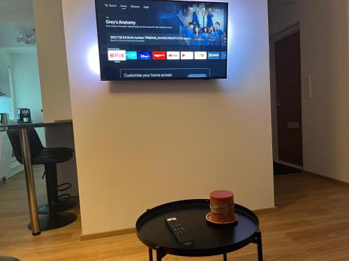 a tv on a wall with a table and a remote control at Cosy apartment in the heart of Lahti, free parking in Lahti