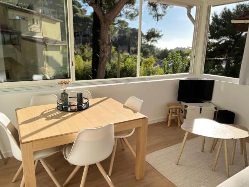 a dining room with a table and chairs and windows at Cabanon contemporain - Côte bleue - Calanque de la Redonne in Ensuès-la-Redonne