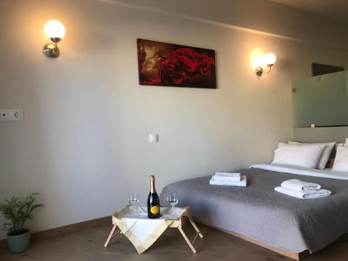 um quarto com uma cama e uma mesa com uma garrafa de vinho em D. Apartments em Kalamata