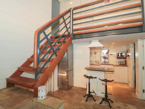 a spiral staircase in a kitchen with two stools at Pips Hideaway in Blandford Forum