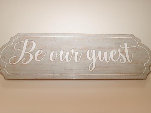 a sign that says be our guest hanging on a wall at Pips Hideaway in Blandford Forum