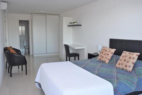 a bedroom with a bed and chairs and a desk at SYRAH Vistas by depptö in Punta del Este