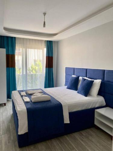 a bedroom with a blue bed with a blue headboard at Palmiye Gold in Çiftlikköy