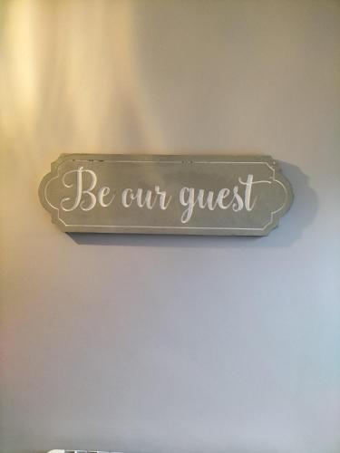 a sign that says be our guest hanging on a wall at Dolmen Apartment Carlingford Lough,Omeath in Ó Méith