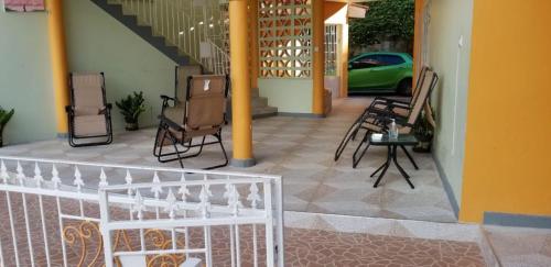 a porch with chairs and a table and a staircase at Chaudhry Holiday House Montego Bay in Montego Bay