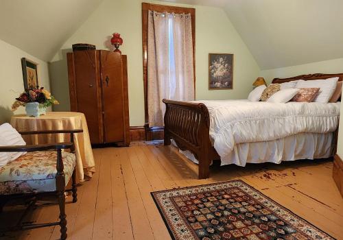 - une chambre avec un lit, une chaise et une table dans l'établissement The Carson House Bed & Breakfast, à Pittsburg