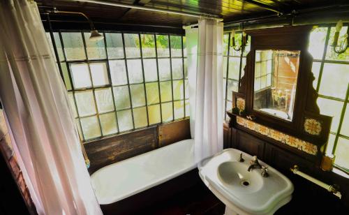 y baño con lavabo y bañera junto a una ventana. en Los Vagones de Areco en San Antonio de Areco