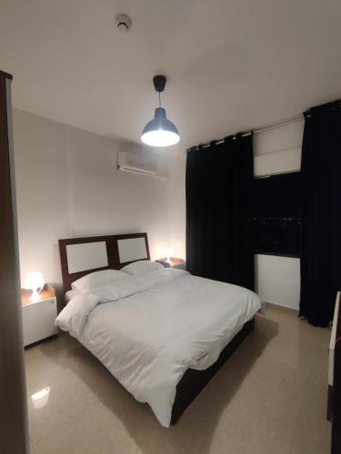 - une chambre avec un grand lit blanc et une lumière dans l'établissement apartment 60m for rent abdullah ghosheh-st jordan, à Umm Uthainah