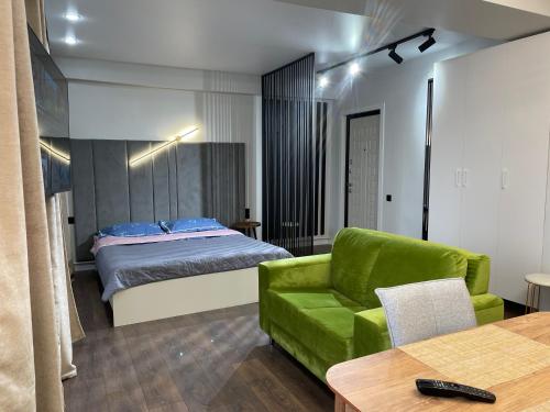 ein Wohnzimmer mit einem Bett und einem grünen Sofa in der Unterkunft Apartment on KShT in Öskemen