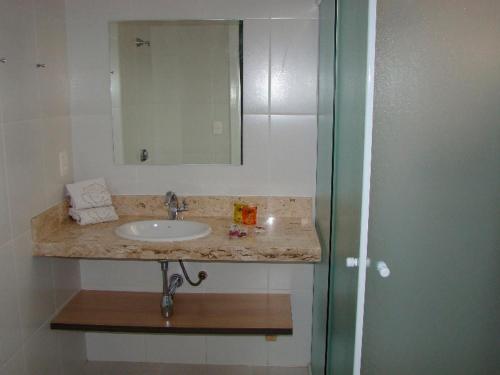 a bathroom with a sink and a mirror at Hotel Rosa da Ilha - Pertinho do Mar com piscina in Guarujá