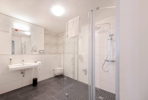 uma casa de banho com um chuveiro, um lavatório e um WC. em Mintrops Concierge Hotel em Essen