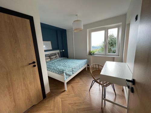 a bedroom with a bed and a table and a window at Apartament Partykularz z tarasem i widokiem na Śnieżkę in Karpacz