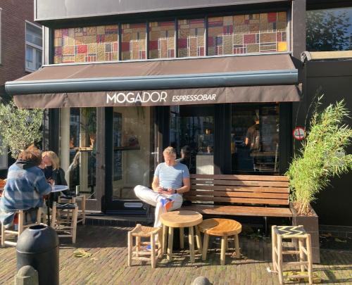 a man sitting on a bench in front of a restaurant at GuesthouseOne in Haarlem