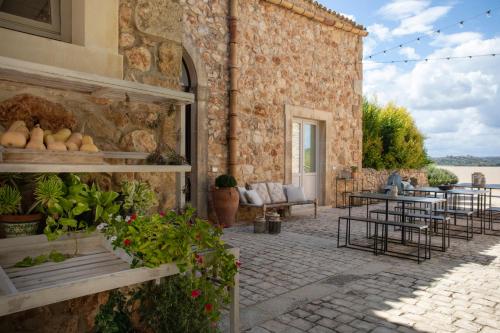 un edificio de piedra con un patio con mesas y sillas en I Carusi Relais, en Noto