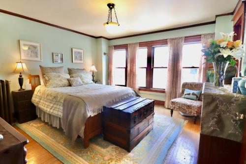 a bedroom with a bed and a chair and windows at The Marshall House in Niagara Falls