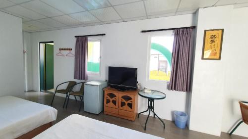 a room with a bed and a tv and a table at Lang Jiao Ya She Homestay in Hengchun