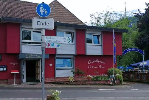 een rood gebouw met een straatbord ervoor bij Gasthaus Goldener Stern in Dorfprozelten