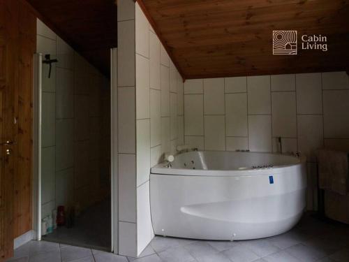 a white tub in a bathroom with a wooden ceiling at Grand cabin at Nesfjellet with lovely view, inddor Jacuzzi & sauna in Nes i Ådal