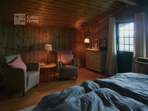 a bedroom with a bed and two chairs and a table at Grand cabin at Nesfjellet with lovely view, inddor Jacuzzi & sauna in Nes i Ådal