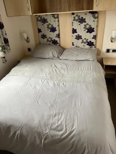 uma grande cama branca num pequeno quarto em F 41 Hutleys Caravan Park em Saint Osyth