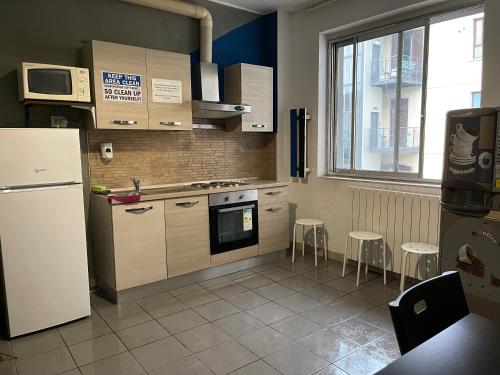 a kitchen with a refrigerator and some stools in it at Ostello Old Milano in Milan