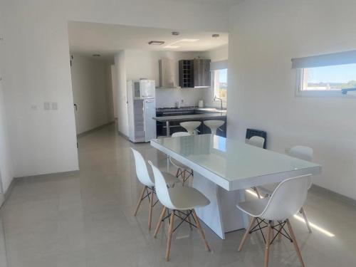 a white kitchen with a white table and chairs at AIRES DEL LAGO, Los Molinos 2 in Potrero de Garay
