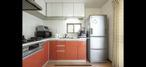 a kitchen with orange cabinets and a refrigerator at 田端民泊ー田端ハウス in Tokyo