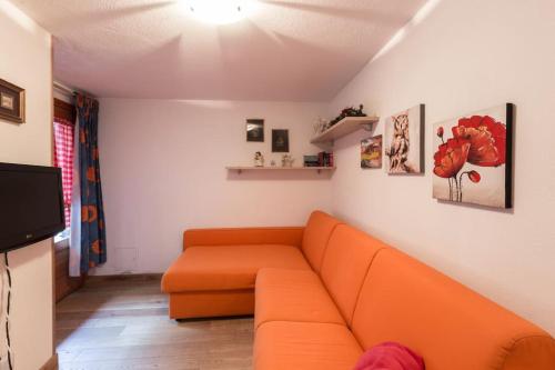 a living room with an orange couch and a tv at Un'oasi nel paradiso Valdostano in Challancin