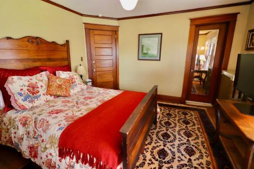 a bedroom with a bed with a red comforter and a television at The Marshall House in Niagara Falls