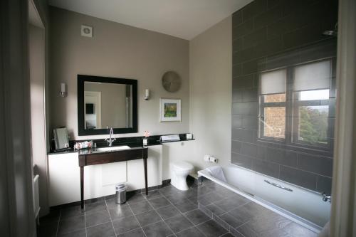 a bathroom with a tub and a sink and a toilet at Hartsfield Manor in Dorking