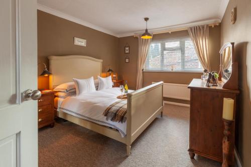 a bedroom with a large bed and a window at Heron Cottage - Norfolk Cottage Agency in Castle Acre