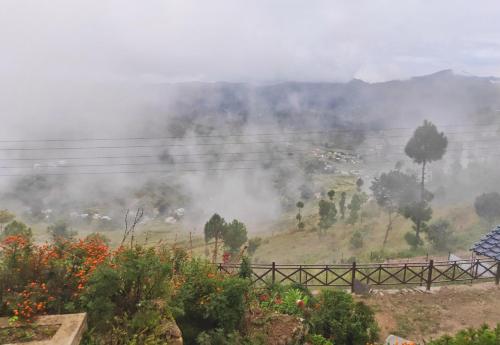 a fire on a hill with smoke in the distance at Meraki Huts in Pauri