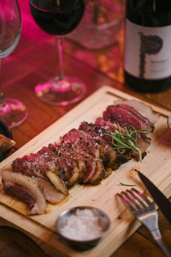 a cutting board with meat and a glass of wine at Casa Gracia in Barcelona