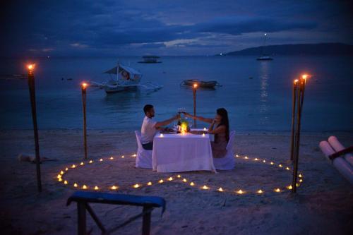 una coppia seduta a un tavolo sulla spiaggia di notte di Natura Vista a Panglao
